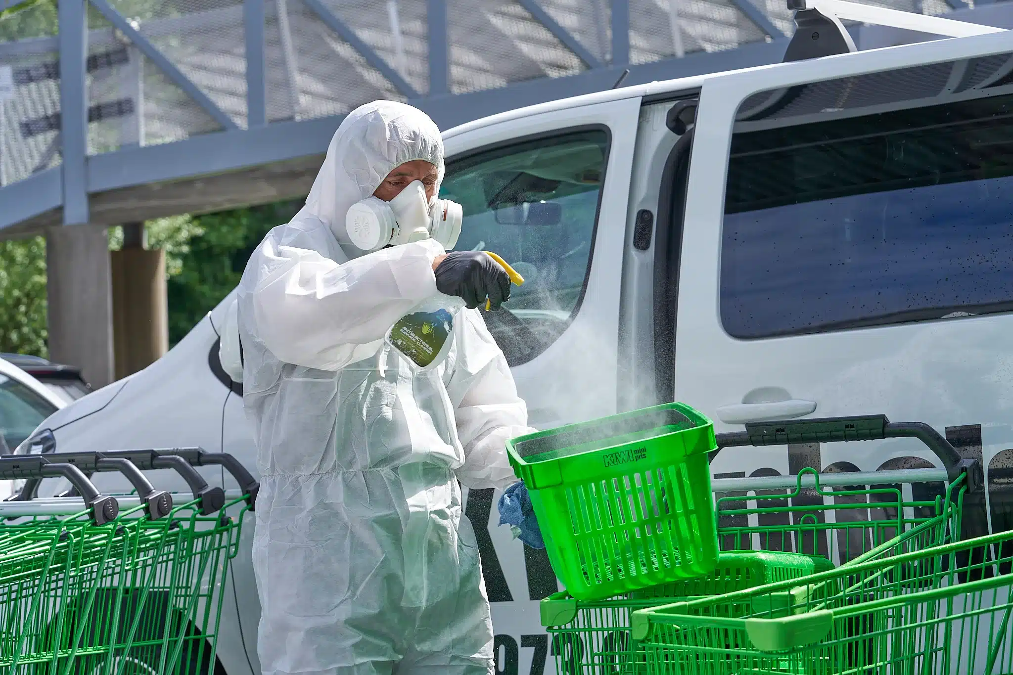 Bilde av en ansatt som sprayer handlekurvene til Kiwi med vaskemiddel